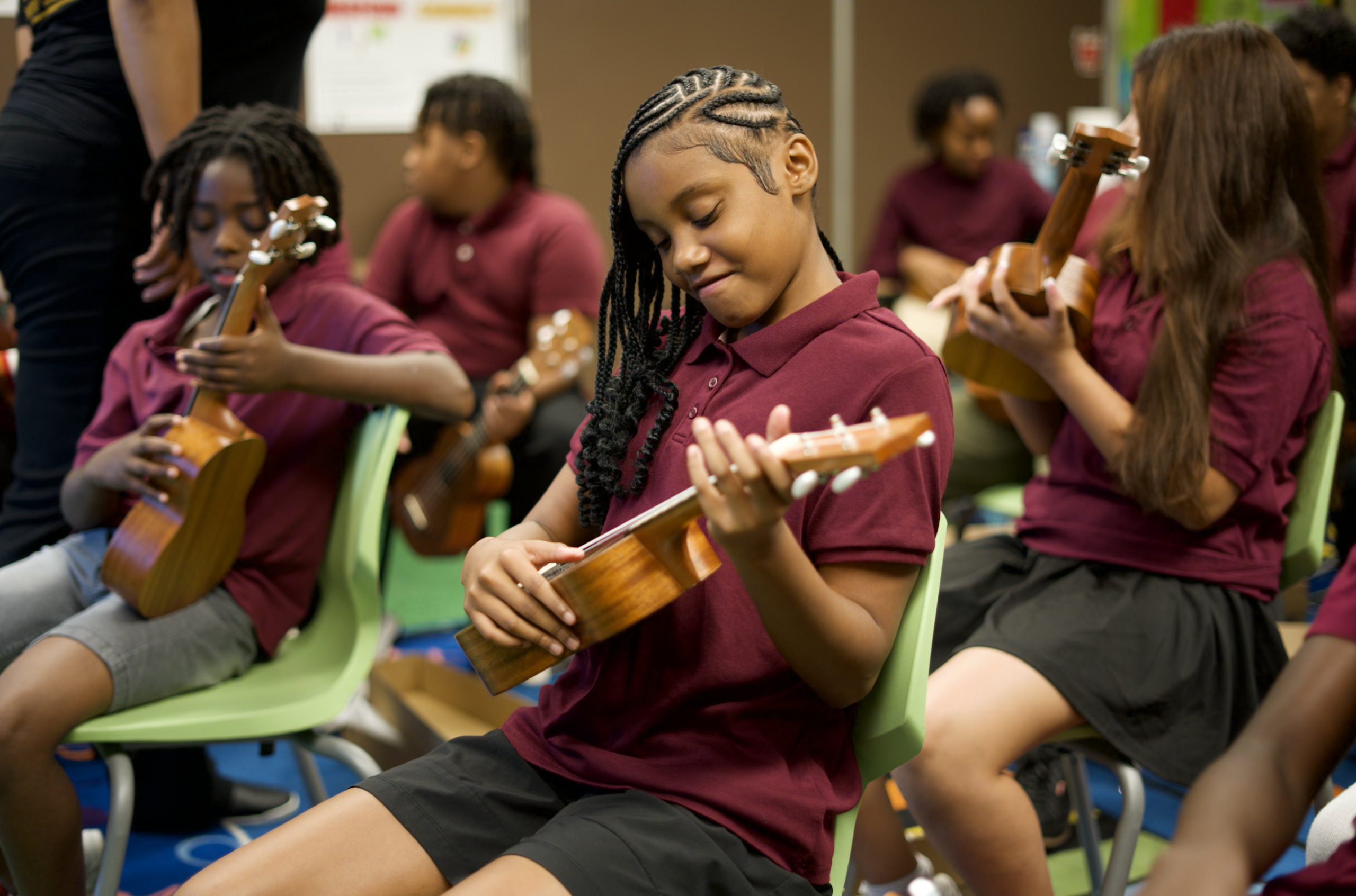 Student playing ukulele in a modern band classroom.