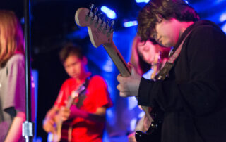 Kid playing electric guitar on stage